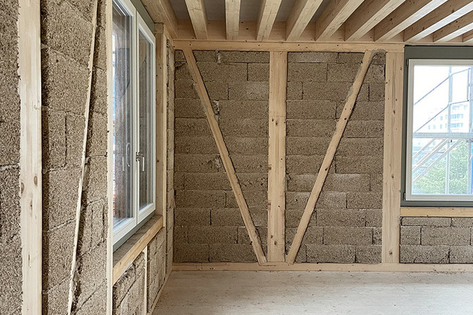 Die Neubauten kombinieren eine Holzständerkonstruktion mit einer Ausfachung aus Hanfkalksteinen und einer vorgelagerten Steinschicht. | © Beat Bühler